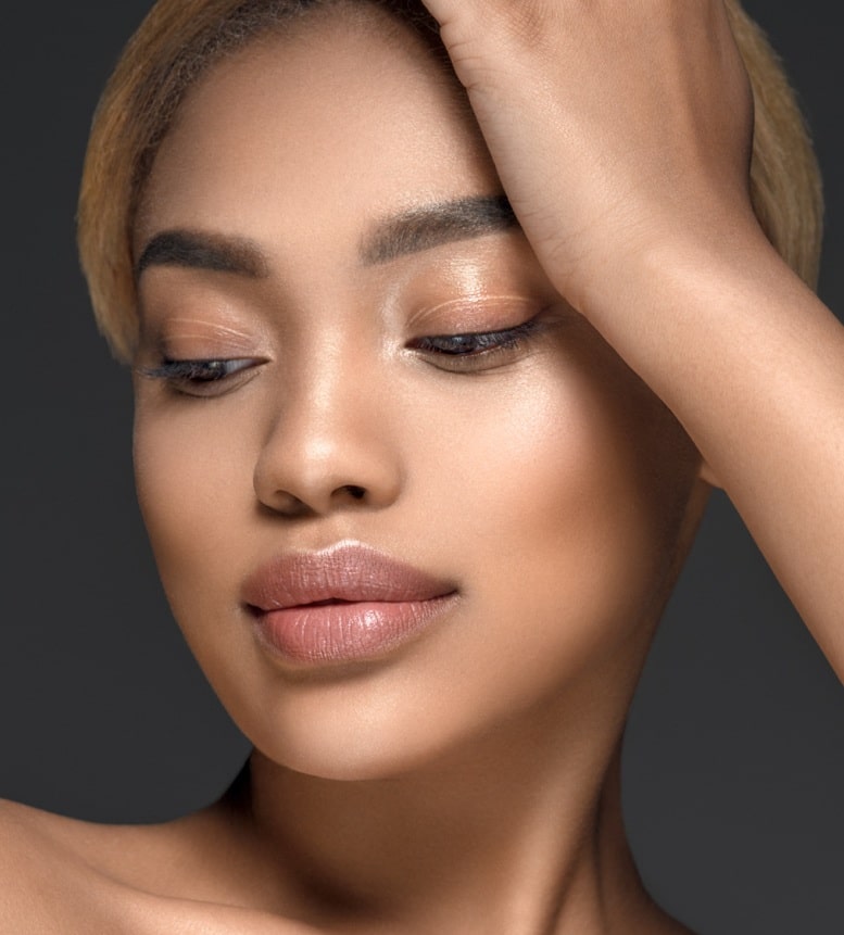 Close up portrait of gorgeous black young beautiful woman with perfect glowing skin, blue eyes, dark hair and minimal nude makeup. Wrinkle Relaxers, Aviva Med Spa Centennial CO.